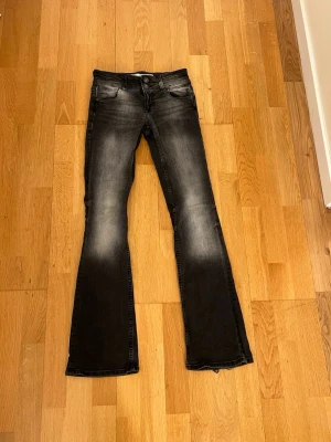 Svarta bootcut jeans med slitningar - Snygga gråa bootcut jeans med slitna detaljer och tvättade partier framtill och baktill. Ner till är dom lite upptrampade 
