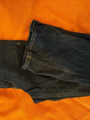 Mörkblå jeans från Perfect Jeans - Snygga mörkblå jeans från Perfect Jeans med klassisk femficksmodell och kontrastsömmar i gult. Jeansen har raka ben och är tillverkade i ett slitstarkt denimtyg som passar perfekt till vardagslooken.