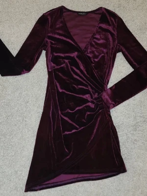 Klänning stl S - Snygg klänning i sammet med omlott-design och v-ringning. Klänningen har långa ärmar och en kort längd som passar perfekt för festliga tillfällen✨️