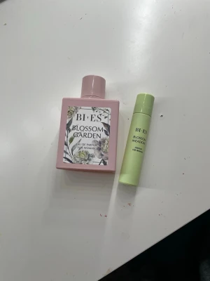 BI-ES Blossom Garden parfymset - Säljer ett parfymset från BI-ES med Blossom Garden EdP i en fyrkantig, matt rosa glasflaska och en Blossom Meadow miniparfym i ljusgrön tub. Båda är för kvinnor och har blommiga doftnoter. Perfekt att ha både hemma och på språng.