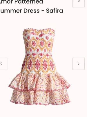 Mönstrad kortklänning  - Supersöt kortklänning från Design by amor med strapless design och volangkjol. Klänningen är storlek S men är väldigt stretchig så skulle säga att den passar XS, S och M. Används 1 gång