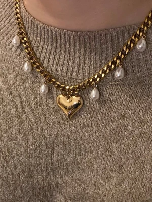 Guldfärgat halsband med pärlor och hjärta - Snyggt guldfärgat halsband med chunky kedja, dekorerat med vita droppformade pärlor och ett stort hjärtformat hänge i mitten. Perfekt för dig som vill ha ett statement-smycke med cool och romantisk vibe. Materialet är rostfritt och pärlor.