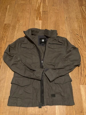 Olivgrön overshirt/jacka - Snygg olivgrön overshirt/jacka från G-Star RAW med flera fickor. Xs. Mycket bra skick. Perfekt för vår och sena sommarkvällar 