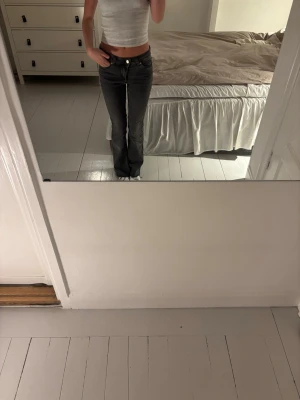 Mörkgrå bootcut jeans - Säljer ett par mörkgrå bootcut jeans med låg midja och klassiska fem fickor. Jeansen har en snygg tvätt och sitter tajt över låren för att sedan bli vidare nedtill. Perfekta för dig som gillar en trendig och avslappnad stil.