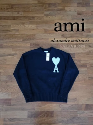 Marinblå Ami Paris Sweatshirt  - Marinblå Ami Paris Sweatshirt – Storlek M, Nyskick Stilren sweatshirt från Ami Paris i djup marinblå nyans med ikoniskt hjärta + “A”-brodyr på bröstet. Mjuk och bekväm passform med ribbade ärmslut och midja. Perfekt för vardag eller uppklädd casual-stil. Märkesetikett och originaltaggar sitter kvar, plagget är i nyskick. 📦 Snabb leverans – skickas samma dag (om ej hinder). Kontakta för frågor!