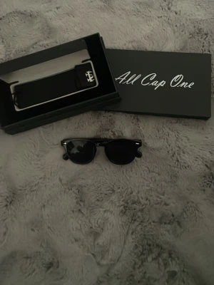 Svarta solglasögon All Cap One - Snygga svarta solglasögon från All Cap One med klassisk rundad form. Kommer i originaletui och box. Glasögonen har en stilren design med mörka linser och passar perfekt till en trendig look. Kontakta mig vid prisförslag/mer bilder/ frågor. Nypris 349 kr! Ej använda!! 