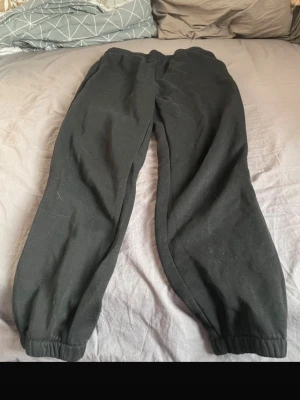 Svarta mjukisbyxor med resår - Svarta mjukisbyxor med resår i midjan och vid bensluten. Klassisk avslappnad passform, perfekta för chill eller träning. Tillverkade i mjukt material som känns skönt mot huden.
