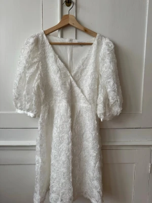 Vit klänning med 3d blommor - Supersöt vit klänning från Bubbleroom , storlek XS. Superfint skick , endast använd vid 1 examen.  Klänningen är perfekt till skolavslutning eller andra festliga tillställningar