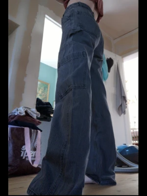 Baggy cargo-jeans  - Säljer ett par cargobyxor i denim med high waist och vida, raka ben. Byxorna har stora sidofickor och bakfickor med tydliga sömmar. Tycker de faller så otroligt snyggt på benen. Säljes pga garderobs rensning. 