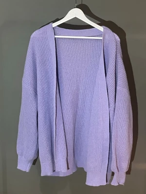Ljuslila oversized stickad kofta - Mysig oversized kofta i ljuslila med ribbstickad struktur. Koftan har långa ärmar med breda muddar och öppen framsida utan knappar. Perfekt för lager på lager och en chill look. Använd fåtal gånger 🪻