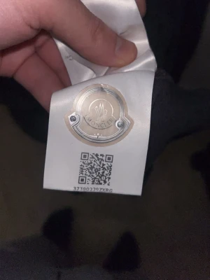 Mörkgrå Moncler långärmad skjorta - Snygg mörkgrå långärmad skjorta från Moncler med klassisk krage och knappar framtill. Skjortan har Moncler-logga på bröstet och diskreta röda och vita detaljer på krage och ärmslut. Tillverkad i mjuk bomull som känns skön mot huden. Köpt för 2,200kr och har ingen användning för den. 