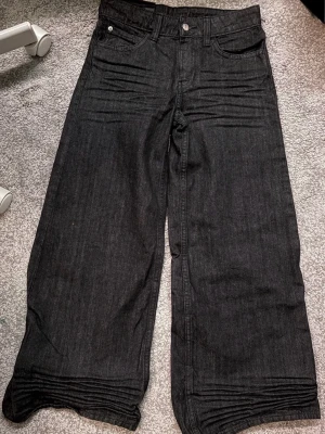 Urban outfitters Svarta wide leg jeans mid waist - Säljer ett par svarta jeans med mid waist och breda ben. Aldrig används med lappen kvar. Dem är ganska korta (jag är 167cm). Perfekta för dig som gillar en avslappnad och trendig look.