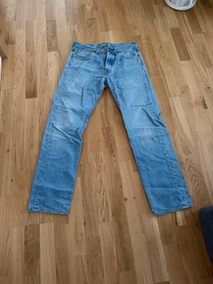 Levi's 501 jeans w31 L32 - Säljer ett par klassiska ljusblå Levi's jeans med rak passform och fem fickor. Jeansen har en ikonisk läderpatch bak i midjan och röd Levi's-tagg på bakfickan. Tillverkade i slitstark denim, perfekta för en avslappnad och tidlös stil.