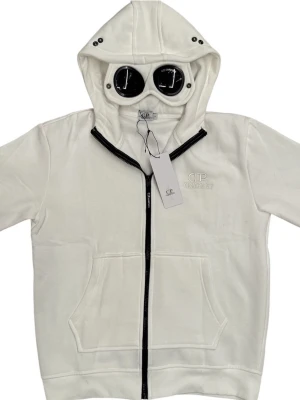 Vit hoodie från C.P. Company - Snygg vit hoodie från C.P. Company med dragkedja framtill och klassisk huva med svarta detaljer. Hoodien har två stora fickor framtill och diskret logga broderad på bröstet. Perfekt för en clean och stilren look. Den är liten är i storlek, egentligen är den storlek L fast den sitter som storlek M. Ny med tags