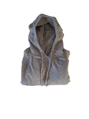Grå hoodie i merino blend - En klassisk grå hoodie med huva och dragsko. Tillverkad i mjukt material som känns skönt mot huden. Hoodien har långa ärmar och ribbade muddar vid ärmslut och nederkant. Perfekt för en avslappnad och chill stil.
