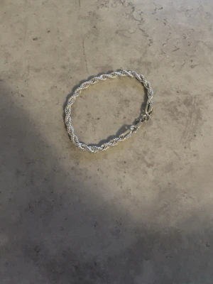 Silvrigt tvinnat armband - Snyggt armband i silverfärgad metall med tvinnad kedja och karbinlås. Armbandet har en stilren och modern look som passar till många olika stilar. Perfekt accessoar för dig som gillar minimalistiska smycken. Den är aldrig några få gånger och priset är billigt eftersom använder den aldrig så vill att den säljs snabbt