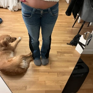 Blå jeans med svarta revärer - Säljer ett par blå jeans med svart jeanstyg som jag har sytt in för att göra det till boo. Byxorna har normal passform och klassisk femficksdesign. Perfekta för dig som vill ha en unik twist på dina vardagsjeans.