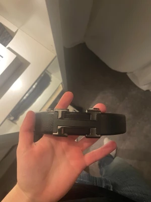 Svart skärp med metallspänne - Snyggt svart skärp från H med ett stort H-format metallspänne i silverfärg. Skärpet är gjort i skinn och har en stilren, klassisk design som passar till många olika outfits.