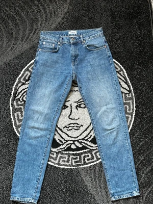 Blå raka jeans från Weekday - Säljer ett par klassiska blå jeans från Weekday med rak passform och fem fickor. Jeansen har en snygg tvättad look och är tillverkade i bomull. Perfekt för dig som gillar enkel och stilren denim.