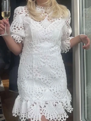 Vit broderad klänning med puffärm - Superfin vit klänning med broderade detaljer och hålmönster. Klänningen har puffärmar, volangkant nertill och rund halsringning. Perfekt för somriga tillfällen och studentfirande. Materialet ser ut att vara bomull eller liknande tyg.