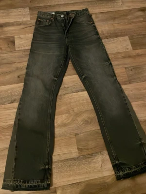 Flared jeans  - Snygga svarta jeans från Zara med raka ben och diskret slitning. Jeansen har klassisk femficksdesign och orangea kontrastsömmar. Perfekta för dig som gillar en avslappnad och trendig look.