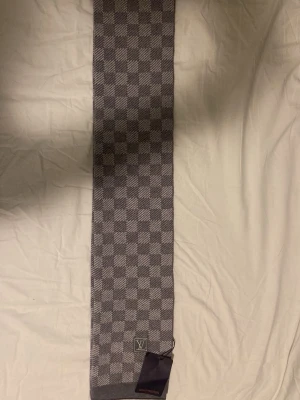 Grå halsduk i ullmix - Säljer en grå halsduk med klassiskt rutmönster i olika nyanser av grått. 