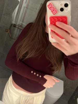 Mörkröd långärmad topp från Zara - Säljer en stilren mörkröd långärmad topp från Zara. Toppen har en enkel och tight passform som passar perfekt till många olika outfits. Materialet känns mjukt och bekvämt mot huden. Perfekt basplagg för garderoben!