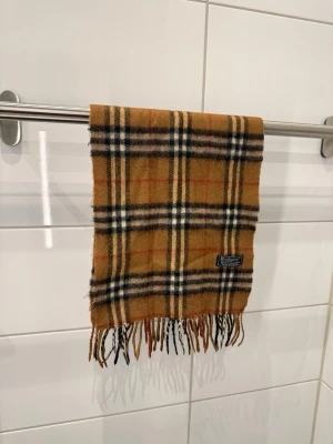 Burberrys Halsduk/Scarf Brun - Burberrys Halsduk/Scarf  Färg: Brun Material: 100% Lammull Unisex  Äldre modell  Fint skick!  #burberry #burberrys #scarf #halsduk