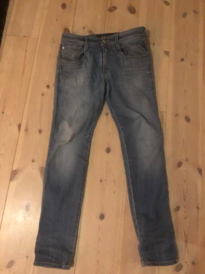 Blå slim fit jeans med slitningar - Snygga blå slim fit jeans med slitna detaljer och klassisk femficksdesign. Jeansen har en något tvättad look och raka ben. Perfekta för en avslappnad och trendig stil. Materialet är troligtvis bomull med lite stretch för extra komfort.