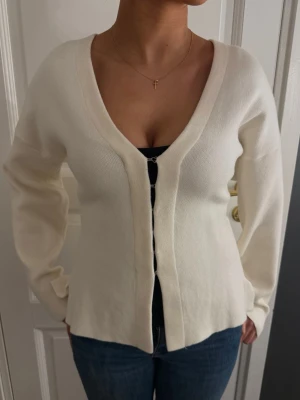 Vit ribbad kofta med v-ringning - Stilren vit kofta med djup v-ringning och långa ärmar. Koftan har en ribbad struktur och stängs framtill med diskreta knappar. Perfekt att bära över ett linne eller t-shirt för en enkel men snygg look 💗💗💗