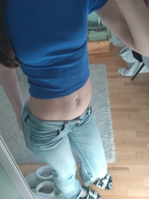 Blå croppad ribbad topp - Snygg croppad topp i klarblå färg med ribbad struktur. Toppen har korta ärmar och en tight passform som framhäver midjan. Perfekt att matcha med jeans eller kjol för en trendig look. Säljer då jag inte bör croppade toppar längre!