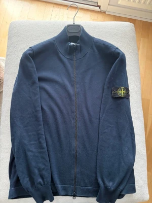 Mörkblå ziptröja från Stone Island - Säljer min Stone Island Ziptröja som jag växt ut något. Används ett fåtal gånger. Mörkblå ziptröja från Stone Island med hög krage och ikonisk patch på vänster ärm. Tröjan har hel dragkedja framtill och ribbade muddar vid ärmslut och nederkant. Perfekt för en clean och stilren look. Vid fler frågor eller mer bilder kontakta gärna mig privat så hjälper jag gärna till😁