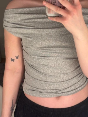 Grå offshoulder topp - Oanvänd grå offshoulder topp med åtsittande passform.