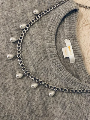 Kedjehalsband med pärldroppar - Snyggt halsband med silverfärgad kedjar rostfritt stål och hängande droppformade pärlor. Kedjan har en chunky känsla och pärlorna ger en elegant touch. Perfekt för dig som gillar att mixa stilar och vill ha något som sticker ut.