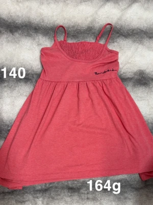 Rosa linnetopp från bondelid - Supersöt rosa linnetopp från bondelid med smala axelband och rynkad överdel. Toppen har ett broderat tryck på bröstet. Perfekt att styla till jeans eller shorts för en chill look.🌸 Fint använt skick. Känns som små noppor på. Storlek 140