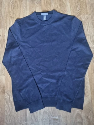 Mörkblå slim fit tröja från H&M - En stilren mörkblå tröja från H&M i slim fit-modell. Tröjan har rund halsringning, långa ärmar och ribbade muddar vid ärmslut och nederkant. Perfekt för dig som gillar en enkel och clean look.