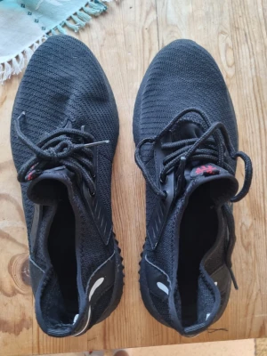 Svarta stickade sneakers med snörning - Svarta sneakers med stickad ovandel och snörning. Skorna har en sportig look med diskreta detaljer och en flexibel sula. Perfekta för dig som gillar en clean och modern stil. Lätta att matcha till olika outfits.