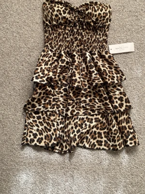 Bandeau klänning - En superfin leopardmönstad klänning utan axelband. Köpt på en butik på Öland men kommer från märket New Collection. Finns ingen storlek på men passar mig som ofta har XS/S. 