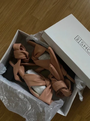 Rosa klackar med knytband  - Helt ny klackskor från Nelly, endast testade. Säljes pga de inte kom till användning på det jag skulle på och nu passar de ej. Klackhöjd 6cm tror jag det var. Man knyter dem kring benen/anklarna. Djur och rökfritt hem, färgen är smutsrosa! 