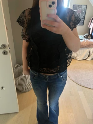 Svart spetsblus - Säljer en svart spetsblus med volangdetaljer och korta ärmar❤️ Jättefin att styla med ett par jeans eller kjol. Använd ett par gånger men är inte alls sliten och är nästan som ny