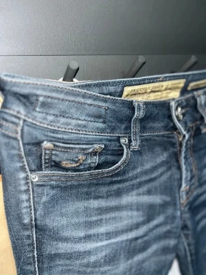 Blå jeans från Jacob Cohen size  - Snygga blå jeans från Jacob Cohen med klassisk femficksdesign och tydliga kontrastsömmar. Jeansen har en mörk tvätt och läderpatch med logga bak i midjan. Perfekta för dig som gillar stilrena och tidlösa jeans.