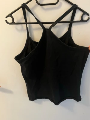 Svart linnetopp från Top Girl - Snygg svart linnetopp från Top Girl med smala axelband och rak passform. Materialet känns mjukt och lätt mot huden.