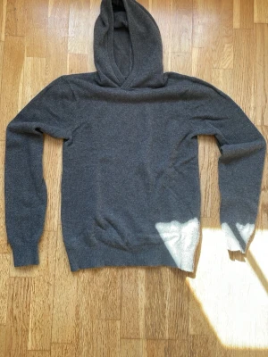 Mörkgrå hoodie i merinoull från Vaillent - Mysig mörkgrå hoodie från Vaillent i mjuk merinoull. Klassisk modell med huva och ribbade muddar vid ärmslut och nederkant. Perfekt för dig som gillar stilrena och bekväma plagg med en lyxig känsla.