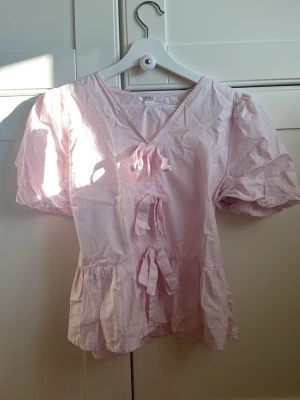 Ljusrosa blus  - Söt ljusrosa blus med korta puffärmar och rosetter från gina young. Pris kan diskuteras💕