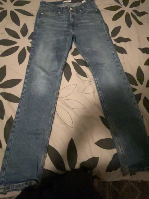 Blå slim fit jeans 30/32 - Snygga blå slim fit jeans med klassisk femficksdesign och raka ben. Jeansen har en lätt tvättad look och kontrastsömmar. Perfekta för dig som gillar en smalare passform och tidlös stil.