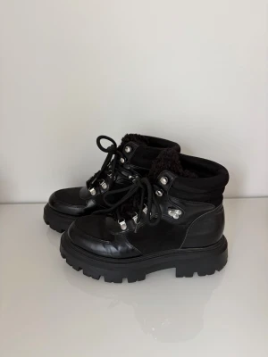Svarta chunky kängor med foder från HM - Används vid ett fåtal tillfällen men är i mycket bra skick!  svarta kängor med grov sula och snörning. Kängorna har detaljer i metall och ett mysigt, svart foder som sticker upp vid skaftet. Perfekta för kalla dagar och ger en cool look till vilken outfit som helst.