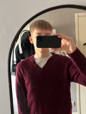Ralph Lauren V neck - Vinröd V-neck stickad tröja från Ralph Lauren med broderad logga på bröstet. Tröjan har långa ärmar och ribbade muddar vid ärmslut och nederkant. Ganska tunn så passar bra nu för sommaren och höst!