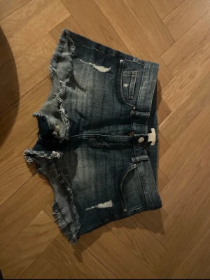 Blå jeansshorts med slitningar - Säljer ett par blå jeansshorts med slitningar knappt använda.