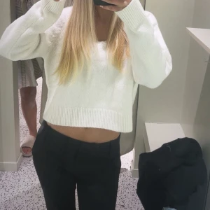 Vit stickad tröja - Säljer en vit croppad stickad tröja med rund hals och långa ärmar. Tröjan har en avslappnad passform och ribbade muddar vid ärmslut och nederkant. Perfekt för en chill och stilren look.