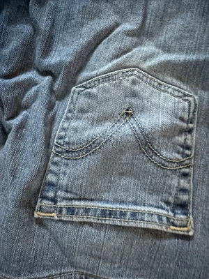 Levi's blå jeans med bakficka - Klassiska blå jeans från Levi's med snyggt bakficksmönster och kontrastsömmar. Tillverkade i bomull med lite elastan för extra komfort. Perfekta för dig som gillar tidlös denimstil.